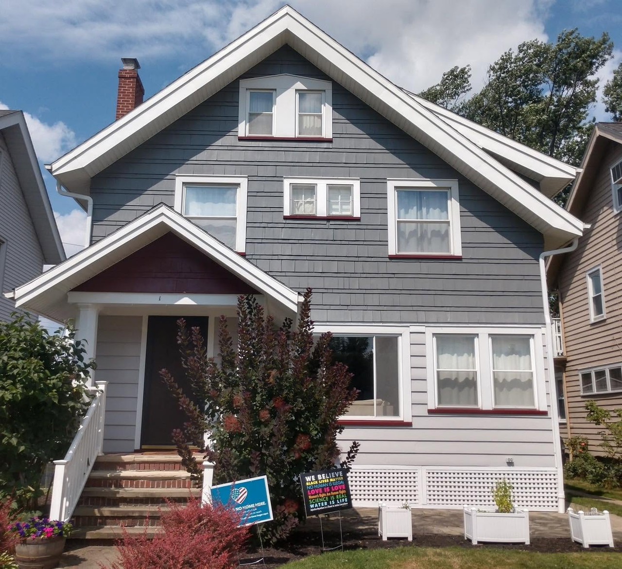 Completed gray gabled home exterior with crisp white trim and a red entry door
