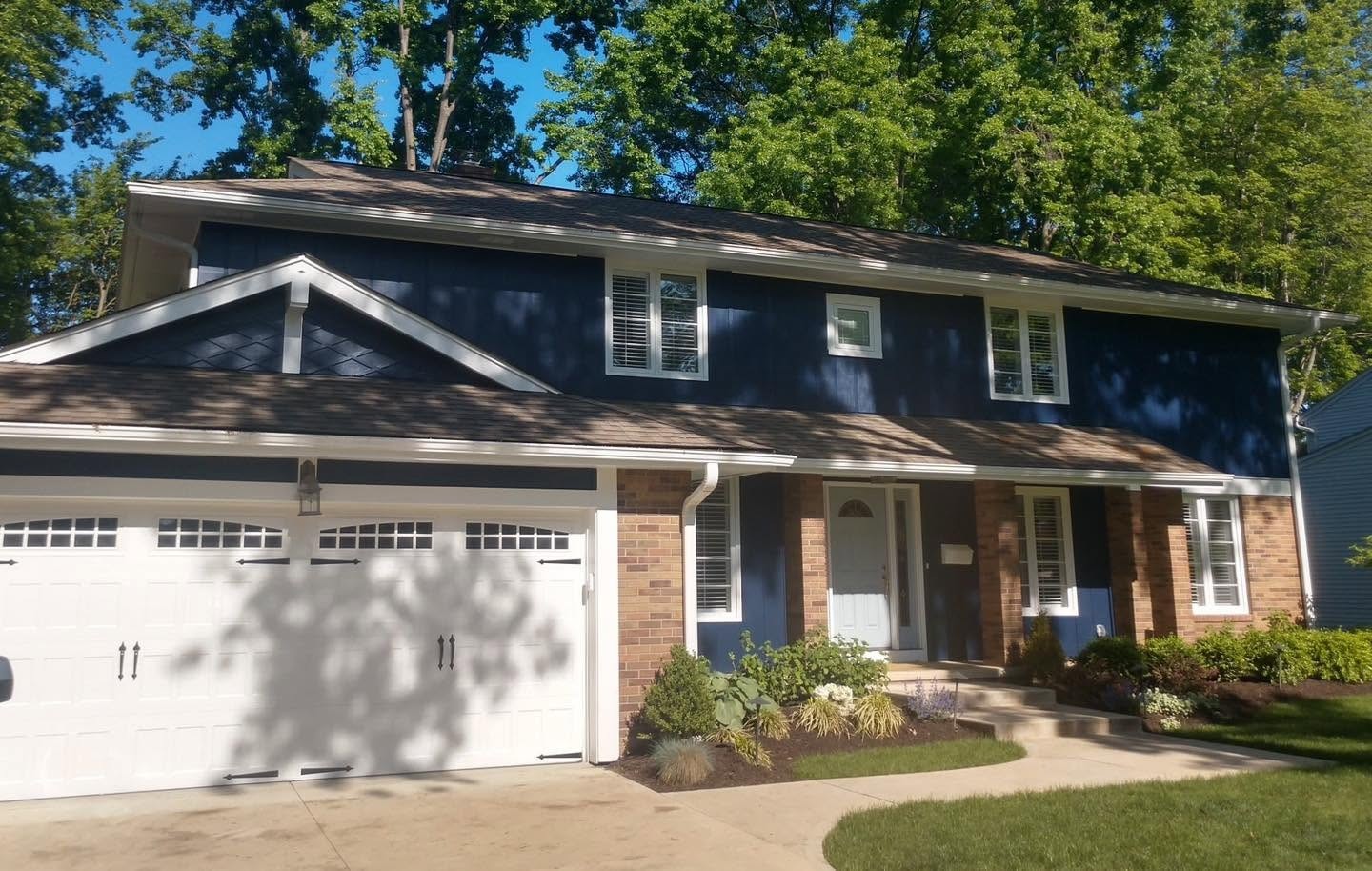 Completed navy-and-white home exterior with a brick lower level