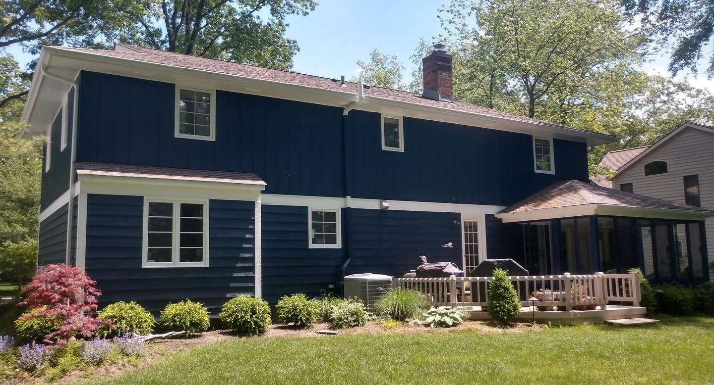 Completed navy-and-white two-story home exterior viewed across a landscaped backyard