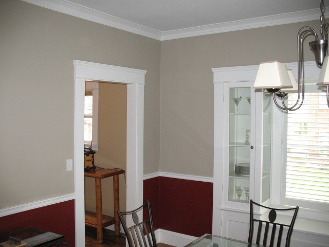 Completed dining room with warm gray walls, deep red lower walls, and crisp white trim