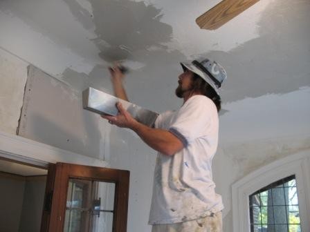 Painter applying a smooth skim coat to a repaired ceiling area