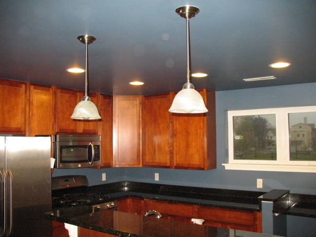 Completed kitchen interior with blue-gray walls, white trim, and wood cabinetry